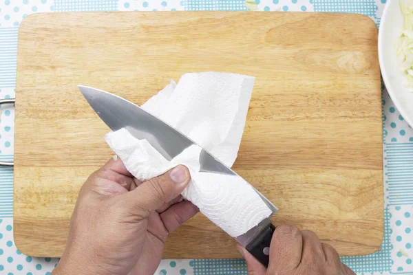 Chef cleaning knife with paper — Stock Photo, Image