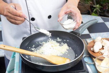 Şef, mantar kreması çorbası ve mantar çorbası konsepti pişirmek için unu tavaya koyuyor.