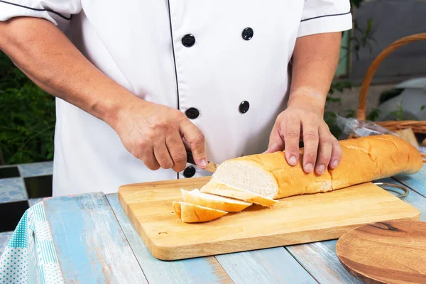厨师持刀切滑块面包在木板上制作 烹饪大蒜面包概念 — 图库照片