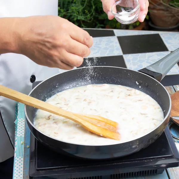 厨师将盐放入锅内烹调蘑菇奶油汤 烹调蘑菇奶油汤的概念 — 图库照片
