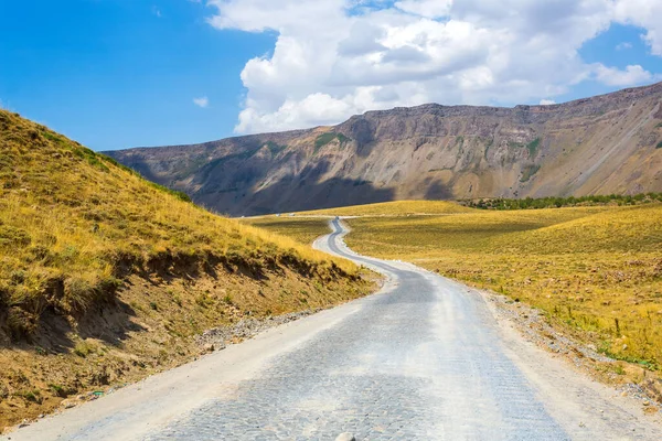 The road among the mountains. Cobbled road in the crater of Nemrut volcano, Bitlis Province, Eastern Turkey. Panoramic view of golden fields, hills and mountains