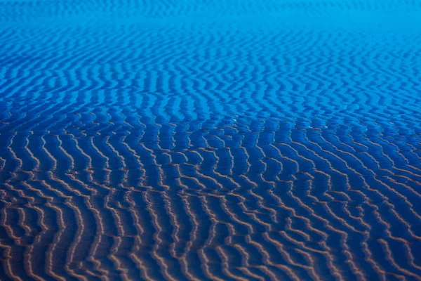 Areia ondulações fundo azul — Fotografia de Stock