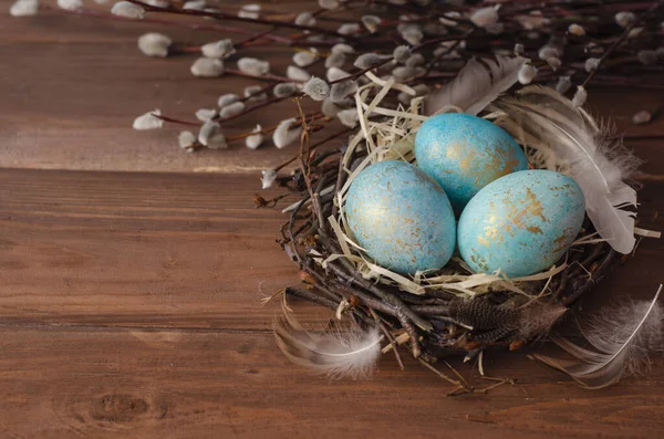 Easter eggs in a nest on blue background. Copy space, Ester holiday postcard concept.