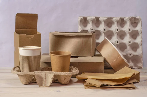 Eko kağıt sofra takımı. Kağıt bardaklar, tabaklar, torbalar, fast food kutuları, teslimat için kutular ve ahşap zemin üzerinde ahşap çatal bıçaklar. Geri dönüşüm konsepti. Sıfır atık.