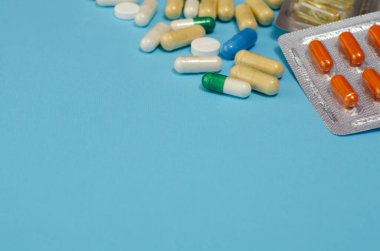 Mavi arka planda izole edilmiş kapsül haplarının tıbbi konsepti. Çeşitli renkli haplar ve kapsüller yakın, yatay, kopyalama alanı, seçici odak, tıbbi konsept. 