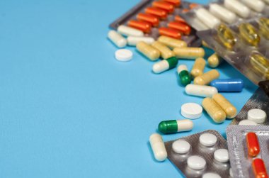 Mavi arka planda izole edilmiş kapsül haplarının tıbbi konsepti. Çeşitli renkli haplar ve kapsüller yakın, yatay, kopyalama alanı, seçici odak, tıbbi konsept. 