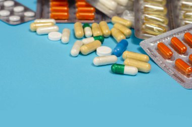 Mavi arka planda izole edilmiş kapsül haplarının tıbbi konsepti. Çeşitli renkli haplar ve kapsüller yakın, yatay, kopyalama alanı, seçici odak, tıbbi konsept. 