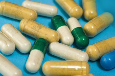 Mavi arka planda izole edilmiş kapsül haplarının tıbbi konsepti. Çeşitli renkli haplar ve kapsüller yakın, yatay, kopyalama alanı, seçici odak, tıbbi konsept. 