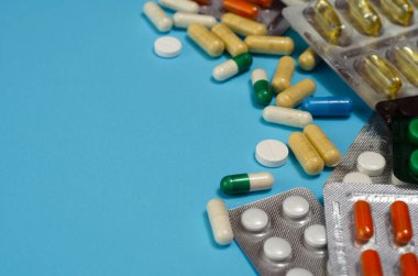 Mavi arka planda izole edilmiş kapsül haplarının tıbbi konsepti. Çeşitli renkli haplar ve kapsüller yakın, yatay, kopyalama alanı, seçici odak, tıbbi konsept. 