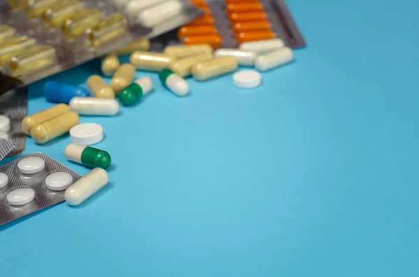 Mavi arka planda izole edilmiş kapsül haplarının tıbbi konsepti. Çeşitli renkli haplar ve kapsüller yakın, yatay, kopyalama alanı, seçici odak, tıbbi konsept. 