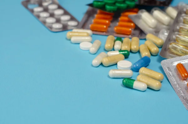 Mavi arka planda izole edilmiş kapsül haplarının tıbbi konsepti. Çeşitli renkli haplar ve kapsüller yakın, yatay, kopyalama alanı, seçici odak, tıbbi konsept. 