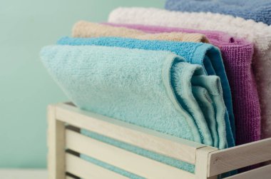 Açık arkaplanda hasır sepette farklı renkte banyo havluları