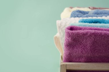 Açık arkaplanda hasır sepette farklı renkte banyo havluları