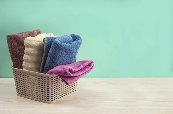 Açık arkaplanda hasır sepette farklı renkte banyo havluları