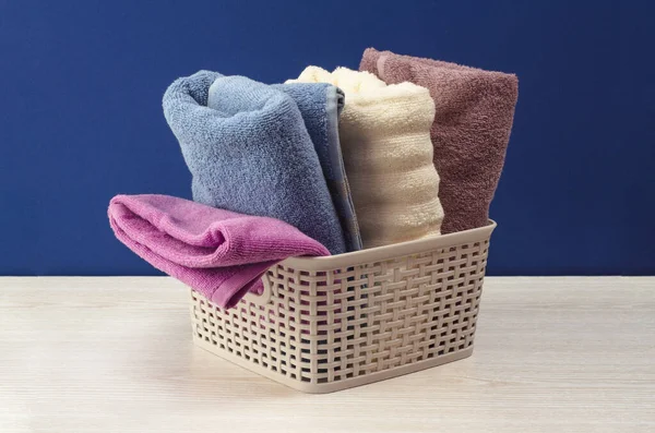 Banyo havluları mavi arkaplanda hasır sepette farklı renktedir.