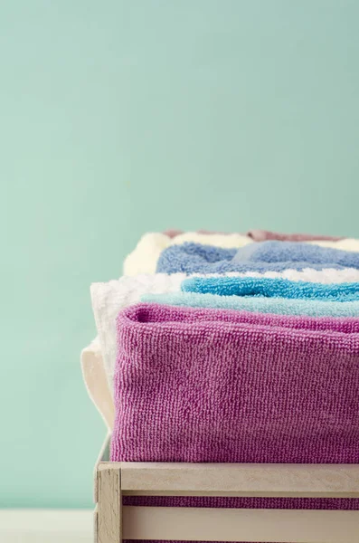 Açık arkaplanda hasır sepette farklı renkte banyo havluları