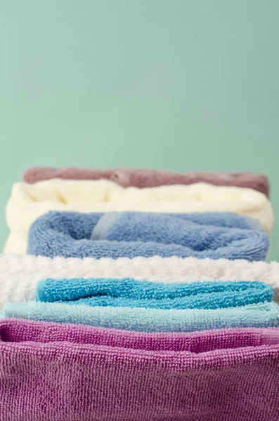 Açık arkaplanda hasır sepette farklı renkte banyo havluları