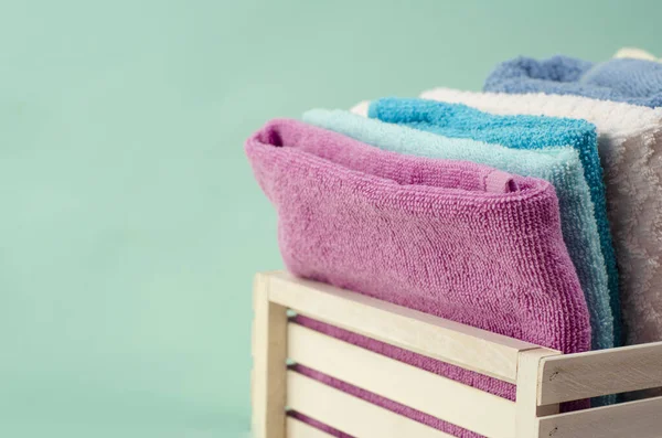 Açık arkaplanda hasır sepette farklı renkte banyo havluları