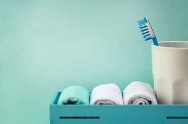 Turkuaz banyo. Beyaz bir pamuk havlu, turkuaz arka planda kavanozda diş fırçası. Kişisel bakım kavramı