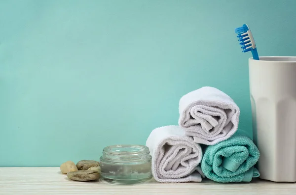 Turkuaz banyo. Beyaz bir pamuk havlu, turkuaz arka planda kavanozda diş fırçası. Kişisel bakım kavramı