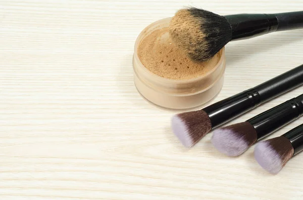 Beyaz arka planda gevşek kozmetik tozu ve yüz için fırça. Makyaj malzemesi. Kozmetik ürünleri.