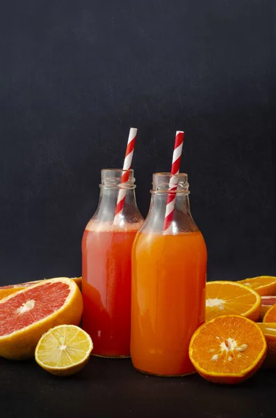 portakal, cam şişelerde greyfurt suyu koyu beton arka planda meyveli