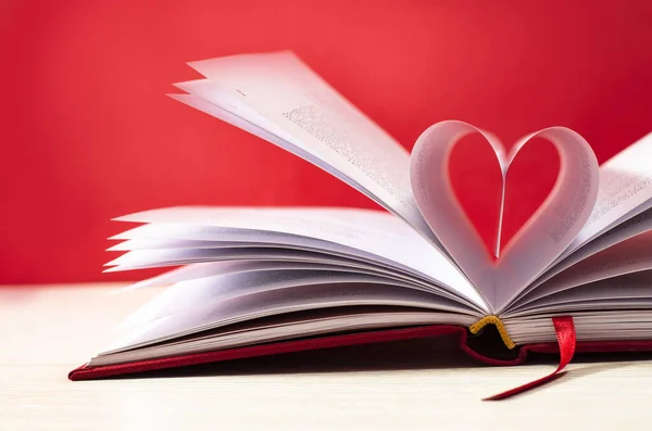 Kırmızı arka planda kalp şeklinde kitap sayfaları. Aşk konsepti