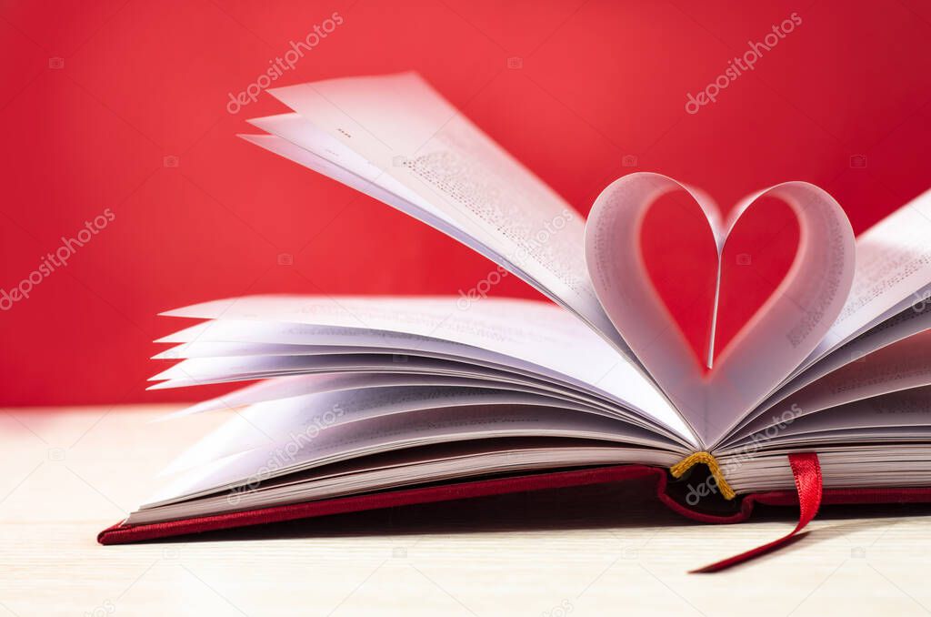 Book pages in shape of heart on red background. Love concept
