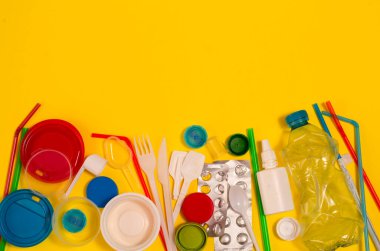 Sarı arka planda beyaz, tek kullanımlık plastik ve diğer plastik eşyalar. Plastik ya da çevresel sorunlar olmadan tercih etme kavramı.