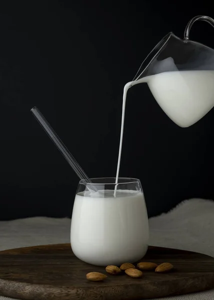Melk wordt in een glas uit een kan gegoten. — Stockfoto