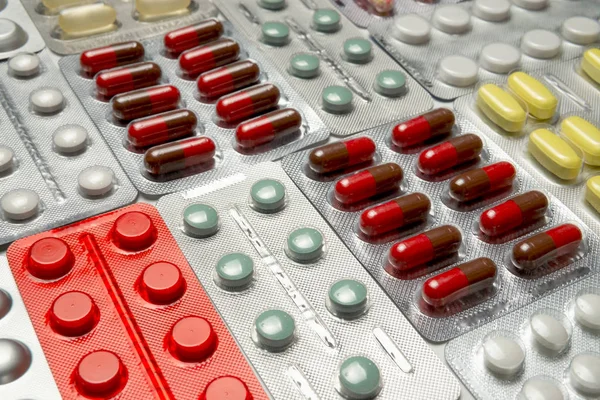 Flerfärgade piller, kapslar och vitaminer i pack bakgrund — Stockfoto