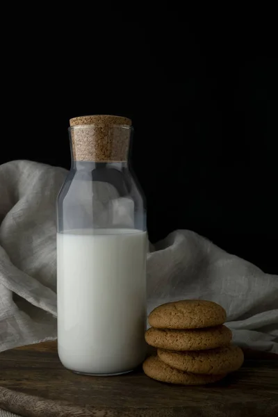 Garrafa de leite e biscoitos de aveia na tábua de corte — Fotografia de Stock