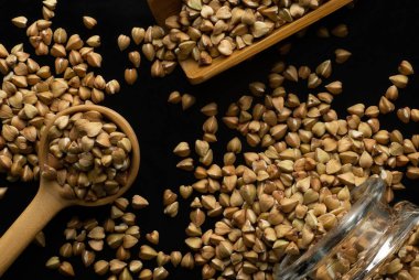 Wooden spoon, wooden scoop and glass jar with buckwheat groats close-up