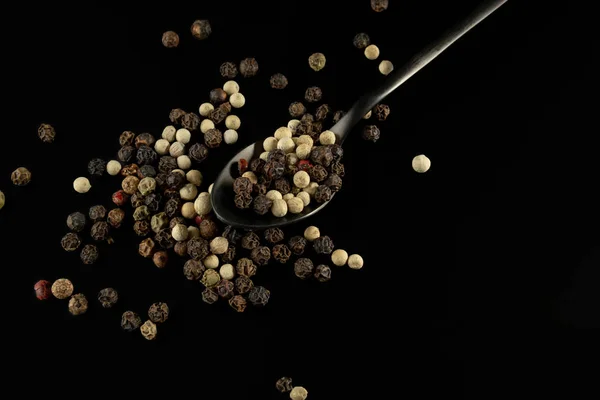 Colored pepper corns and black metal spoon — 스톡 사진