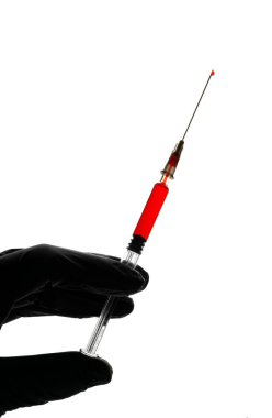 Hand in black glove holds a glass syringe with red liquid on a white background