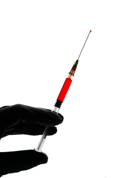 Hand in black glove holds a glass syringe with red liquid on a white background — Stok fotoğraf