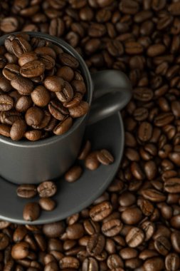 Cup with coffee beans on coffee background. View from above close-up
