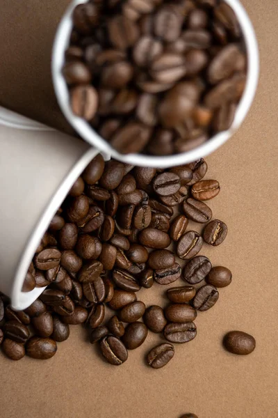 Deux tasses en papier gris remplies de grains de café. Gros plan, plan plat . — Photo