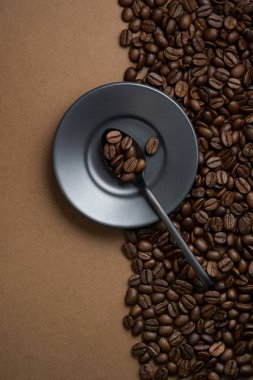 Kahve çekirdekleri çerçeveyi iki parçaya ayırdı ve çay tabağı ve siyah kaşık ile kahve.