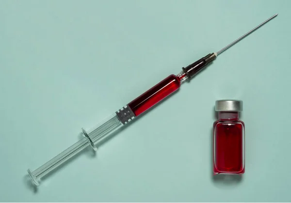 Kırmızı sıvı ile tıbbi kavanoz ve kırmızı sıvı ile cam şırınga — Stok fotoğraf