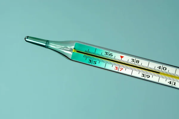Lékařský skleněný teploměr ukazuje vysokou tělesnou teplotu. Detailní záběr na modrém pozadí. — Stock fotografie