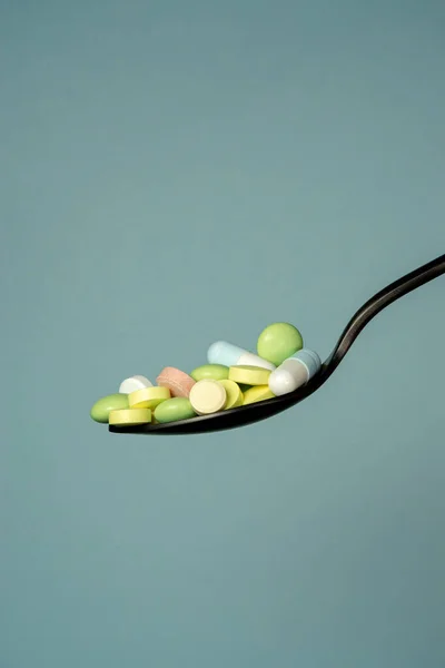 Många flerfärgade tabletter och piller i en svart metallsked — Stockfoto
