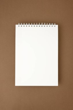 Kahverengi yüzeyde boş beyaz spiral defter