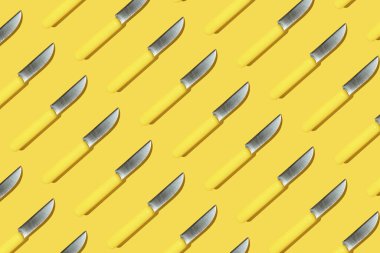 Sarı saplı mutfak bıçakları sarı arka planda paralel, renkli desenli.