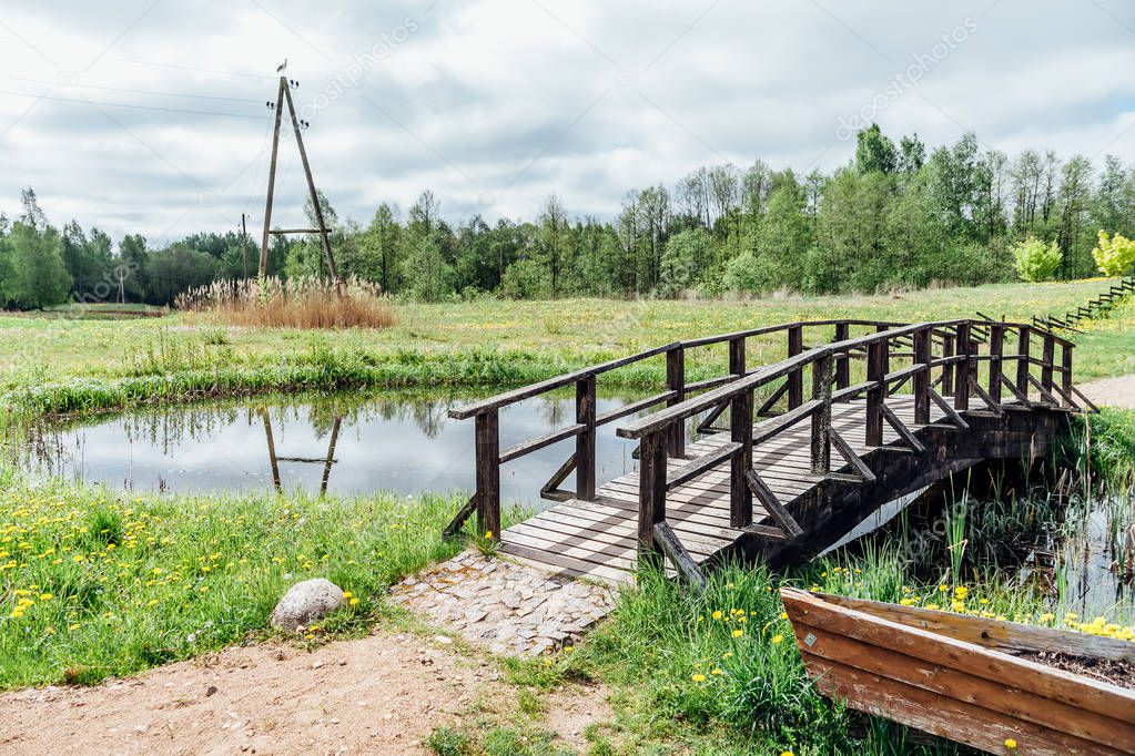 rural country side field with small river and abandoned bridge construction in Latvia