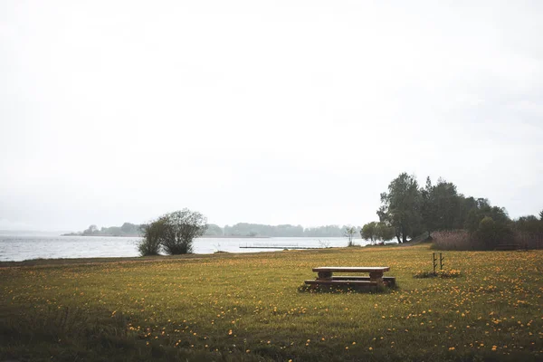 自然をリラックスして楽しむための木製のベンチ付きの穏やかな湖 — ストック写真