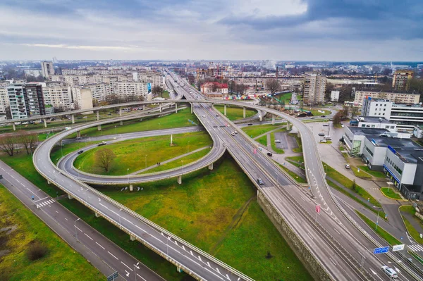 Aerial view at junctions of city highway. Vehicles drive on road