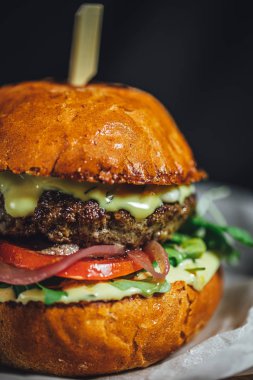 Koyu arkaplanda ahşap tabakta servis edilen mavi peynirli ev yapımı sığır eti burgeri. 