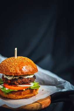 Rucola, soğan, ızgara portobello ve koyu arkaplanda sarımsaklı taze orman burgeri. 