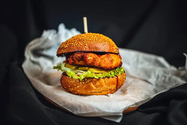 Domatesli ev yapımı tavuk fileto burger, salatalık turşusu ve koyu arkaplanda bbq souce.